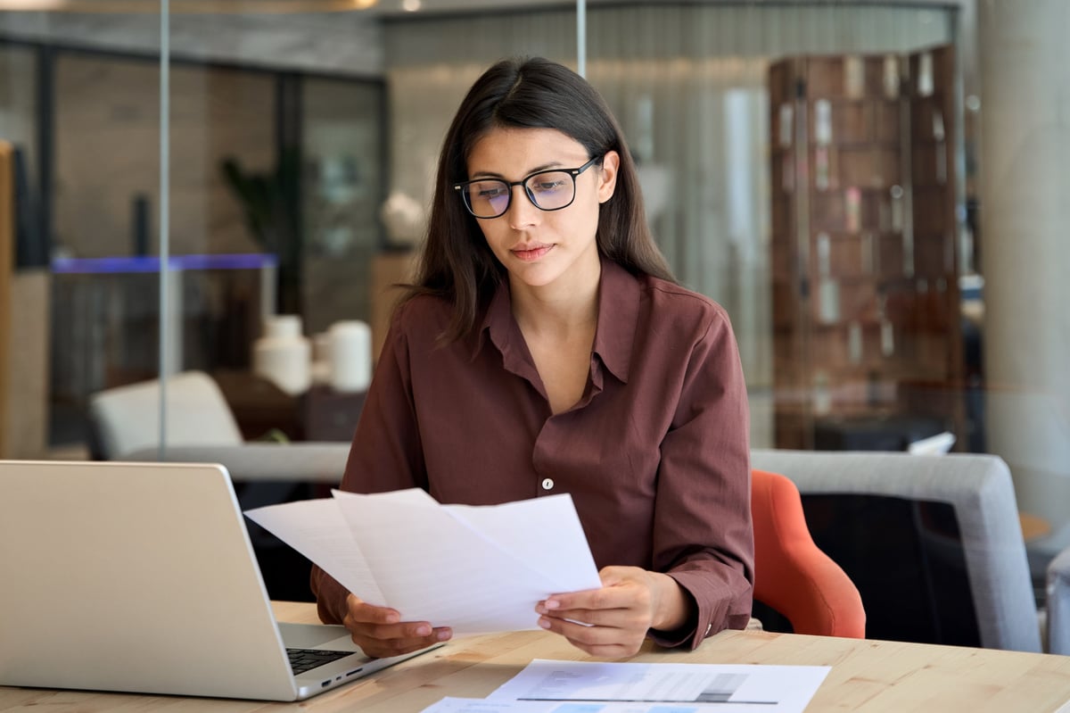 Focused business woman working on financial documents and laptop