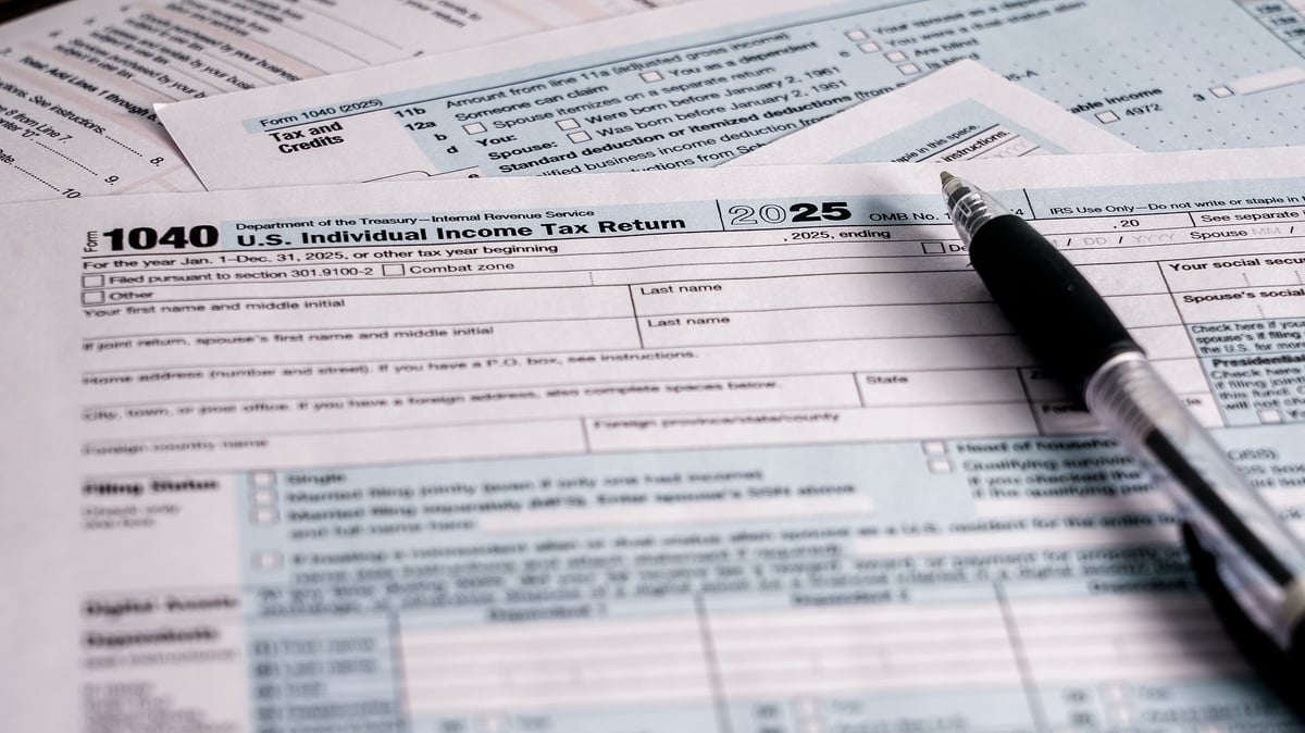 Person working on U.S. individual income tax return with tax forms and pen